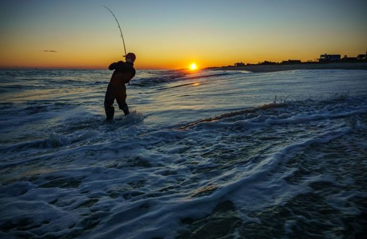 Fishing - silhouette of man fishing on sea during sunset