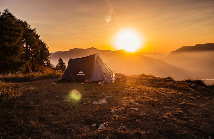Outdoor Gear - dome tent on mountain top with sun as background photo